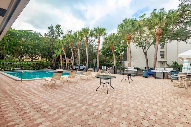 pool featuring a patio area, fence, and a grill