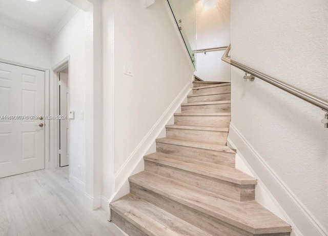 staircase featuring hardwood / wood-style floors and ornamental molding