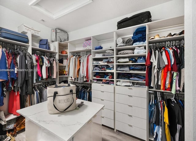 walk in closet with light hardwood / wood-style flooring