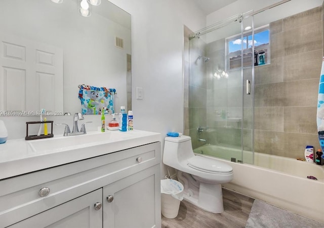 full bathroom featuring toilet, vanity, bath / shower combo with glass door, and hardwood / wood-style floors