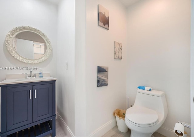 bathroom with hardwood / wood-style flooring, vanity, and toilet