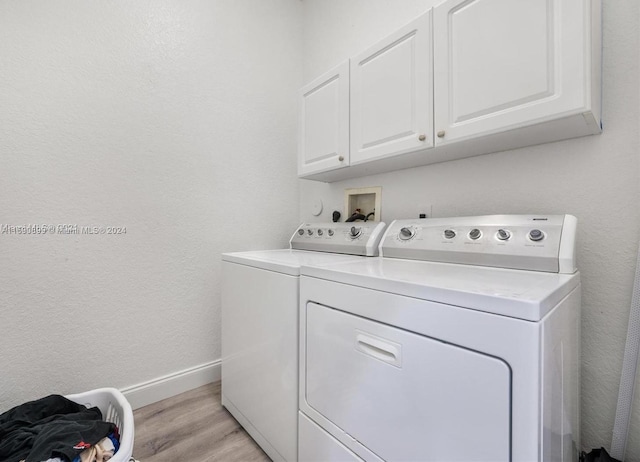 laundry area with cabinets, washing machine and clothes dryer, and light hardwood / wood-style flooring