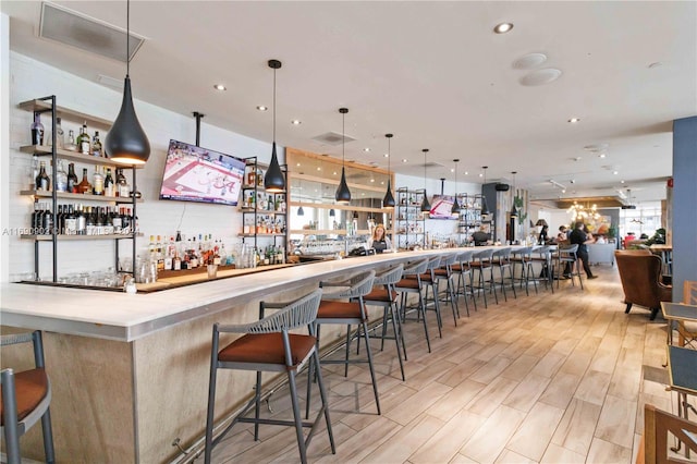 bar with decorative light fixtures and light hardwood / wood-style flooring