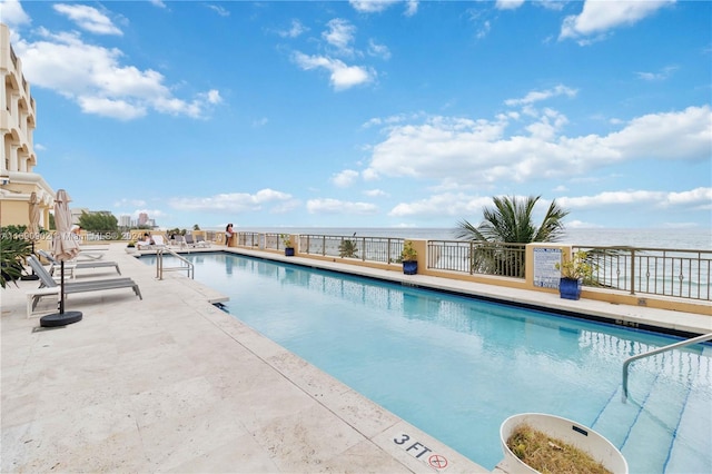 view of swimming pool featuring a water view and a patio