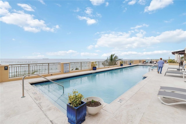 view of swimming pool featuring a patio area and a water view