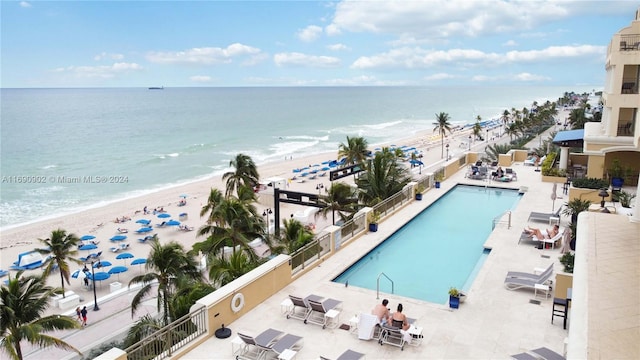 view of swimming pool featuring a view of the beach, a patio, and a water view