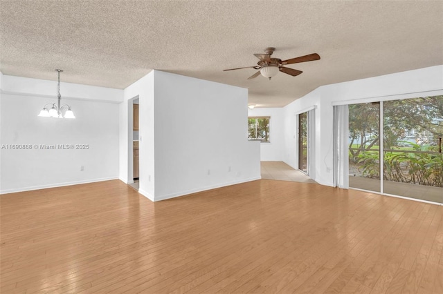 unfurnished living room with light wood finished floors, baseboards, a textured ceiling, and ceiling fan with notable chandelier