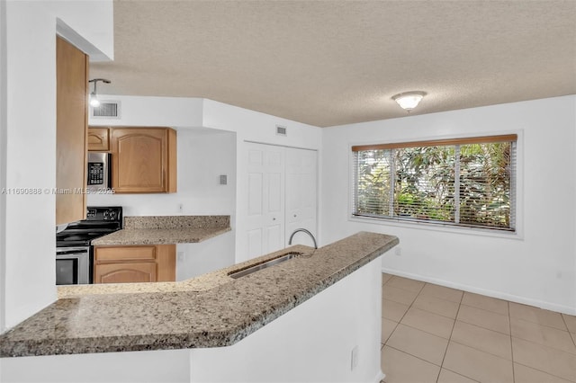 kitchen featuring stainless steel appliances, a sink, a peninsula, and a textured ceiling