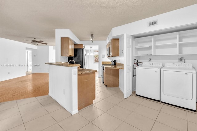 kitchen featuring appliances with stainless steel finishes, brown cabinetry, light tile patterned flooring, and visible vents