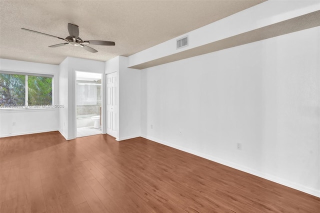 unfurnished room featuring baseboards, visible vents, ceiling fan, dark wood-type flooring, and a textured ceiling