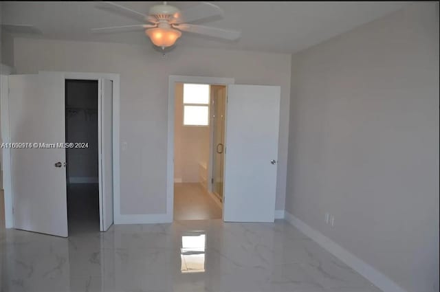 unfurnished bedroom featuring ensuite bath, ceiling fan, a spacious closet, and a closet