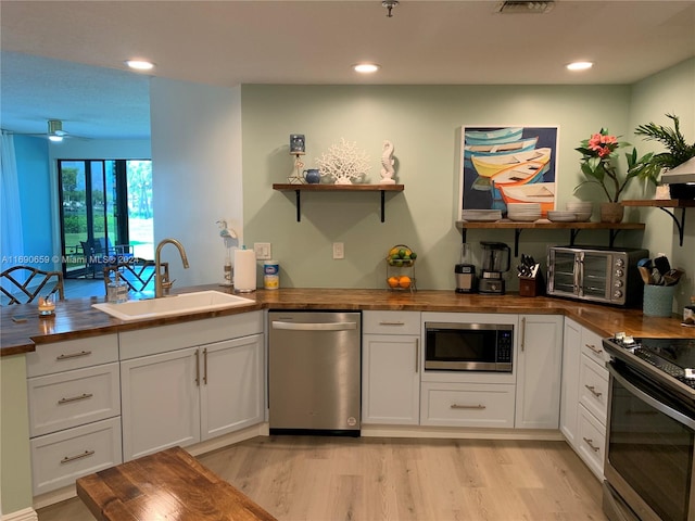 kitchen featuring butcher block counters, white cabinets, sink, and appliances with stainless steel finishes