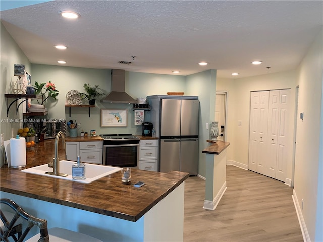 kitchen featuring island range hood, stainless steel appliances, wood counters, sink, and light hardwood / wood-style flooring