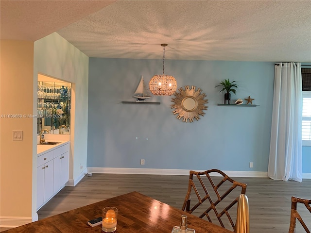 dining space with dark wood-type flooring, sink, and a textured ceiling