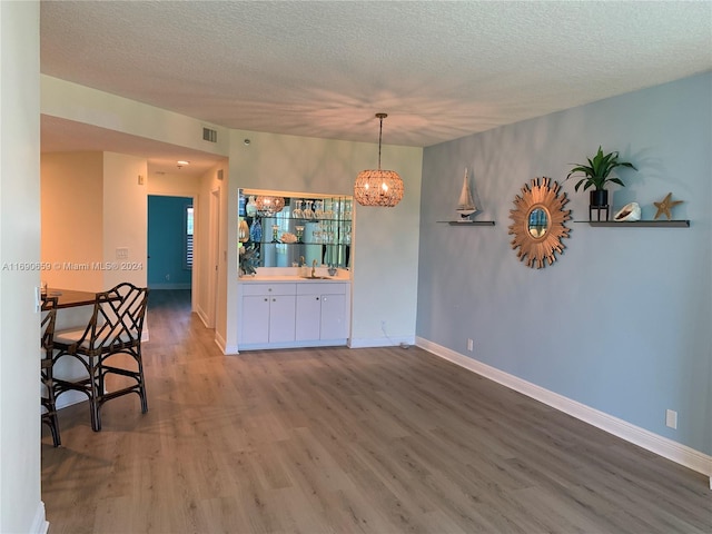 unfurnished dining area featuring an inviting chandelier, hardwood / wood-style floors, and a textured ceiling