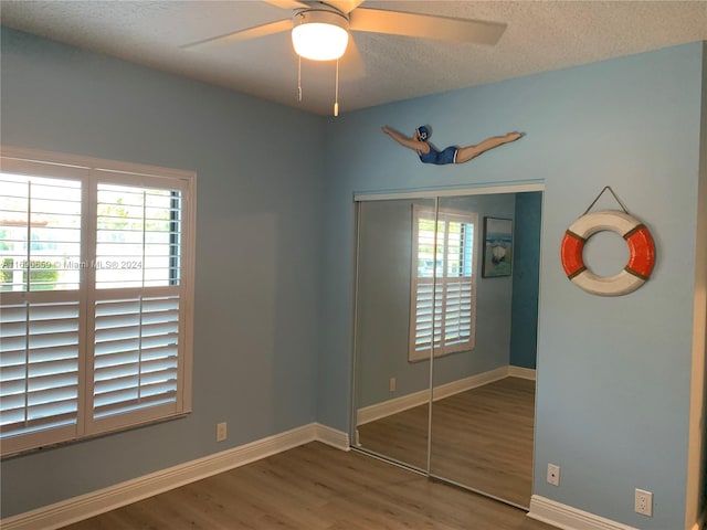 unfurnished bedroom featuring hardwood / wood-style flooring, a textured ceiling, ceiling fan, and a closet