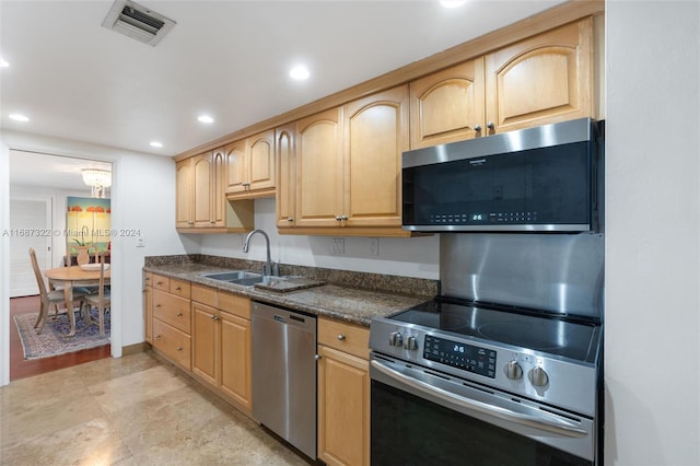 kitchen with appliances with stainless steel finishes, sink, light brown cabinetry, and dark stone countertops