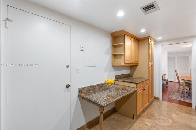 kitchen featuring light hardwood / wood-style flooring, light brown cabinetry, and dark stone countertops