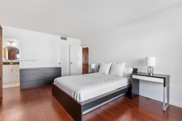 bedroom with dark hardwood / wood-style floors and ensuite bath