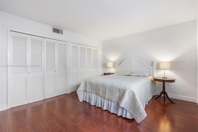 bedroom with dark hardwood / wood-style floors and two closets