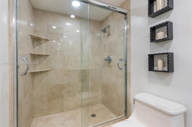 bathroom with a shower with door and toilet