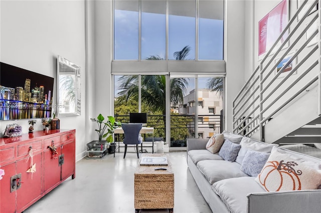 living room with a towering ceiling and concrete floors