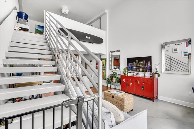 living room with concrete flooring and a towering ceiling