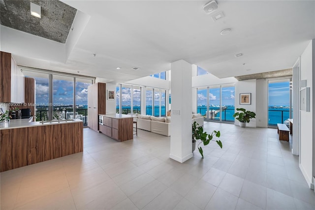 interior space featuring a water view, a wall of windows, and light tile patterned floors