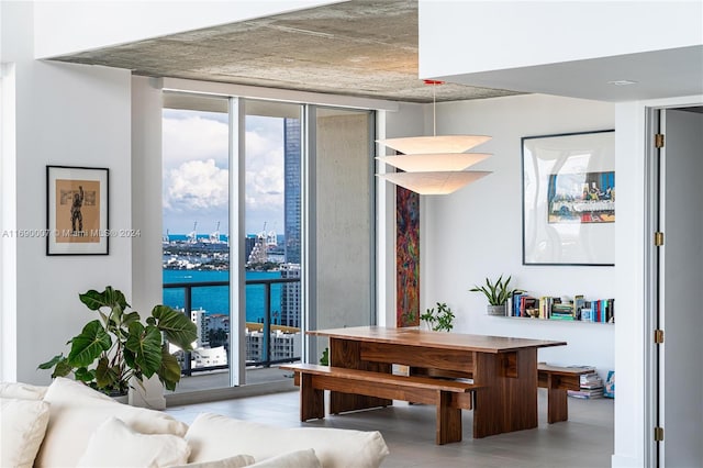 dining area with a wall of windows, a water view, and light hardwood / wood-style flooring