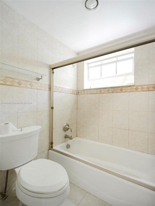 bathroom featuring tile patterned flooring, toilet, tile walls, and tiled shower / bath combo