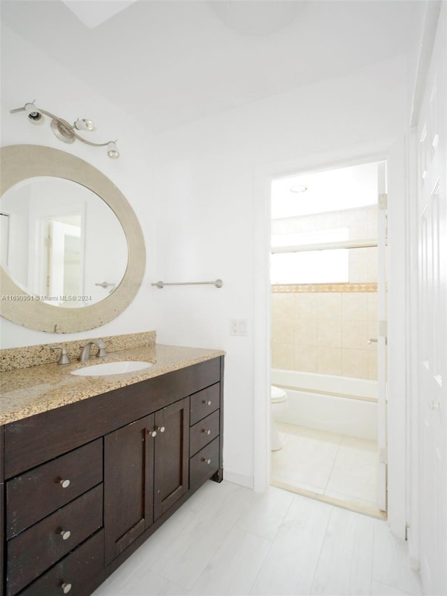 full bathroom with tile patterned flooring, tiled shower / bath, toilet, and vanity