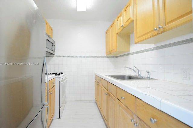 kitchen with tile walls, stainless steel appliances, light tile patterned floors, light brown cabinets, and sink