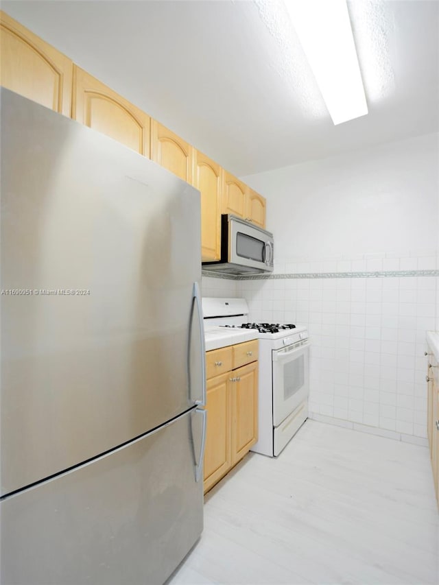 kitchen featuring tile walls, light brown cabinets, and appliances with stainless steel finishes