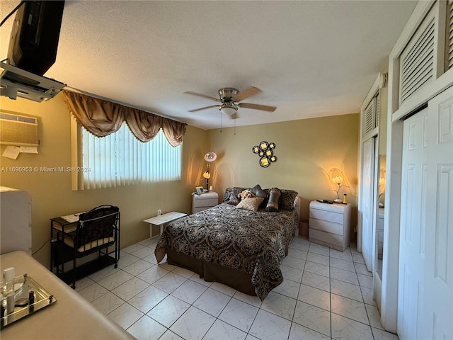 bedroom with a wall unit AC, ceiling fan, a textured ceiling, and a closet