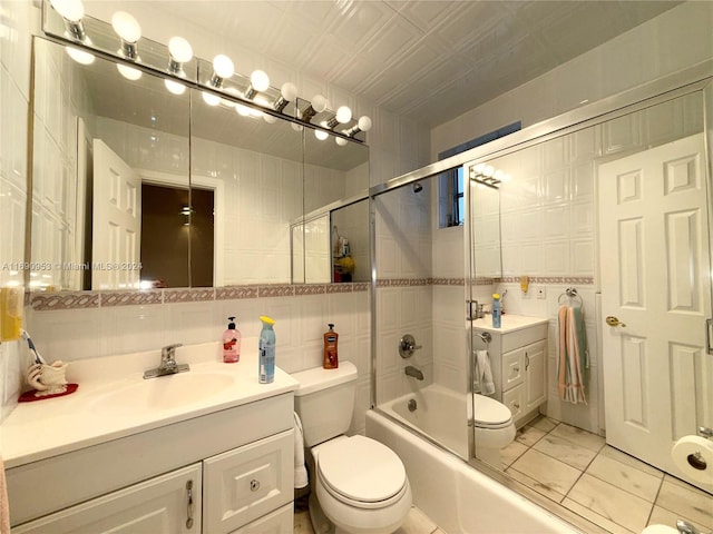 full bathroom with tile walls, backsplash, vanity, bath / shower combo with glass door, and toilet