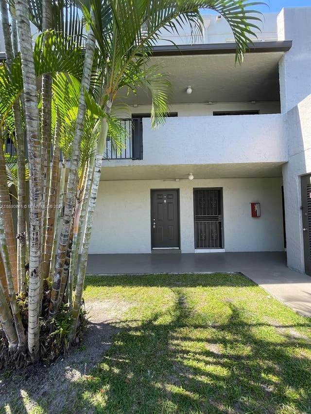 doorway to property with a lawn and stucco siding