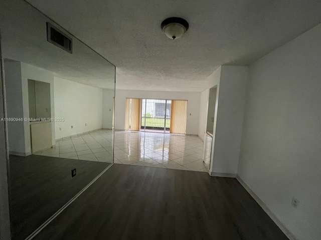 spare room featuring tile patterned floors, a textured ceiling, baseboards, and visible vents