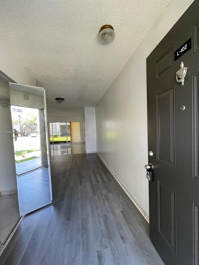 entrance foyer featuring a textured ceiling, baseboards, and wood finished floors