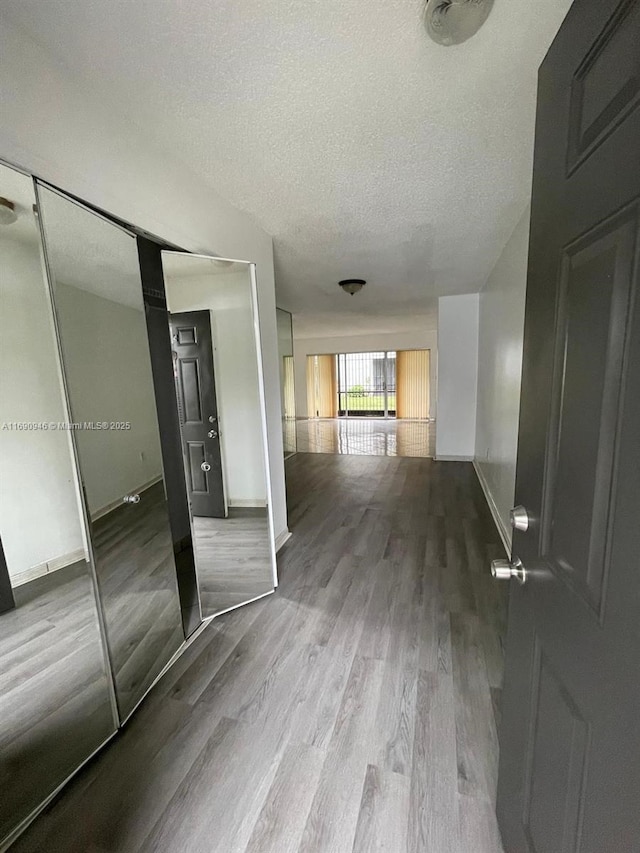 interior space featuring a textured ceiling, baseboards, and wood finished floors
