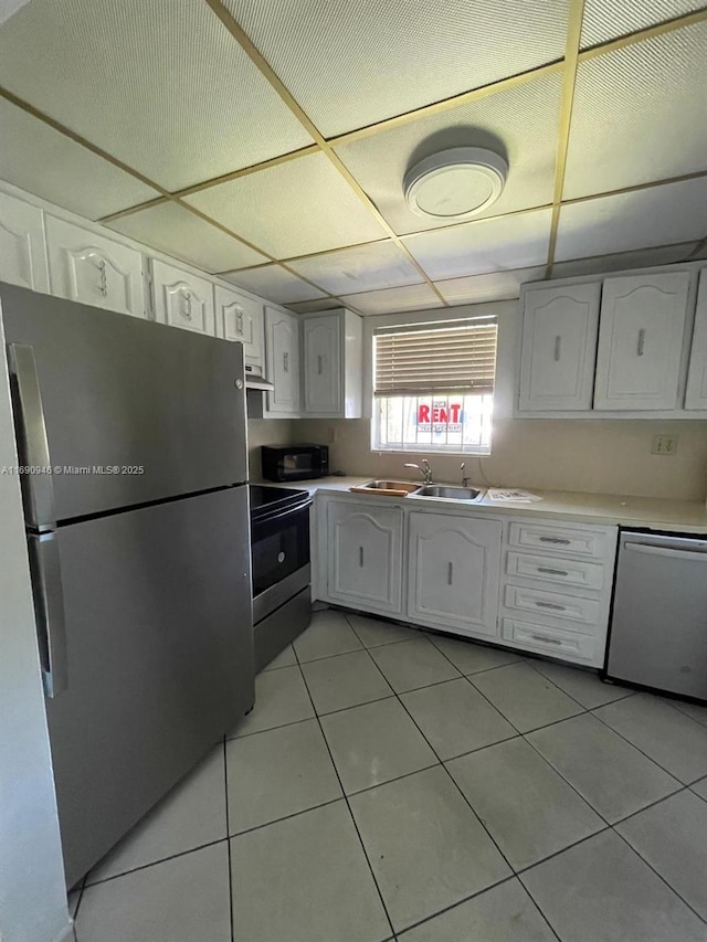 kitchen with white cabinetry, light countertops, a sink, light tile patterned flooring, and appliances with stainless steel finishes