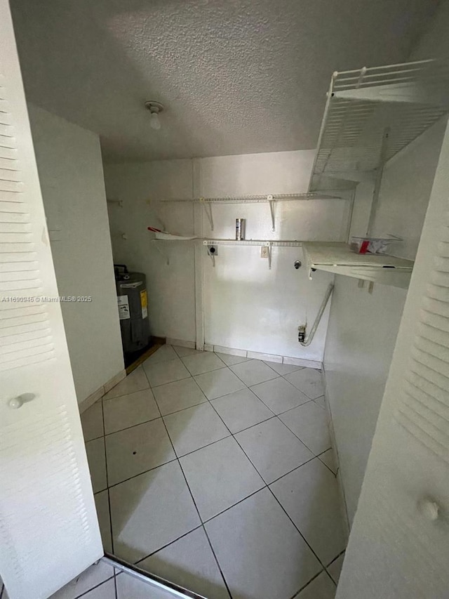 bathroom with tile patterned floors, electric water heater, and a textured ceiling