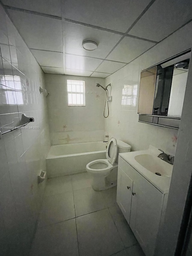 bathroom featuring tile walls, toilet, vanity, tile patterned flooring, and shower / bathtub combination