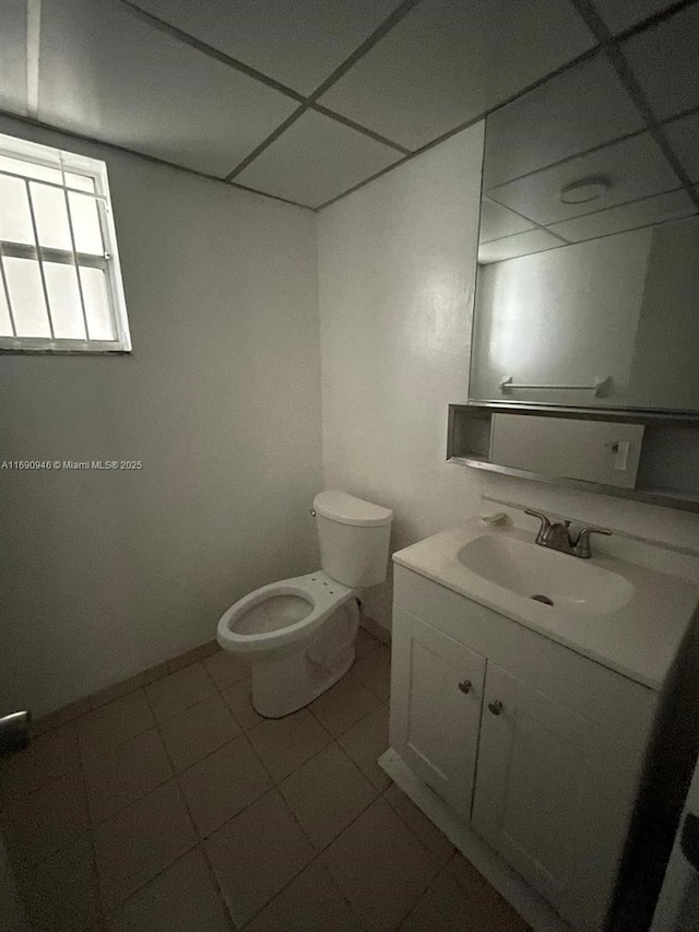 bathroom with baseboards, toilet, a paneled ceiling, and vanity