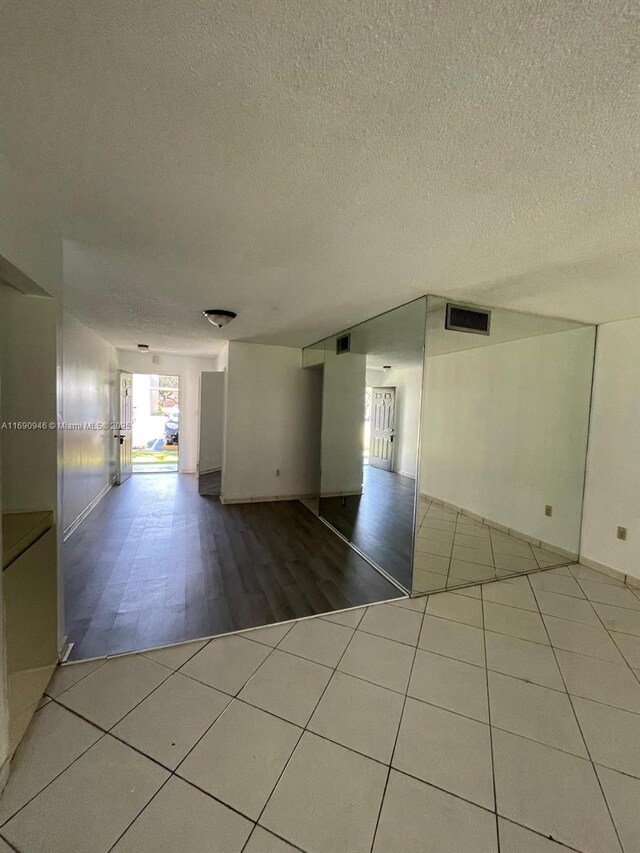 empty room featuring a textured ceiling, visible vents, and tile patterned floors