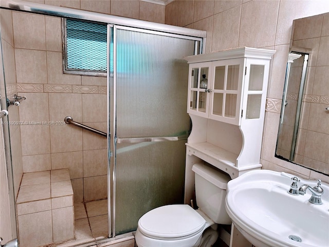 bathroom featuring toilet, sink, and a shower with door