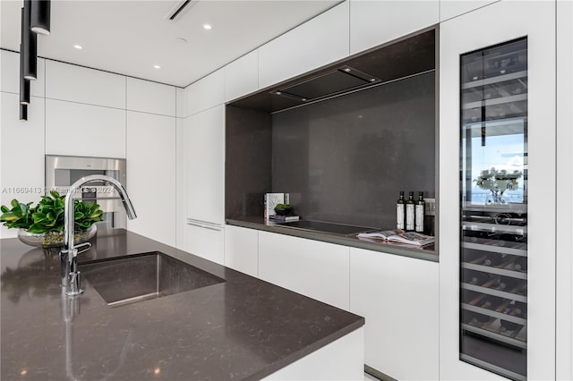 kitchen featuring white cabinets, decorative backsplash, wine cooler, and sink