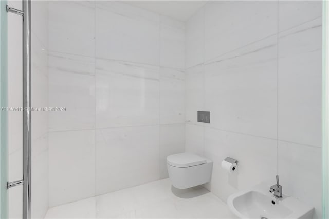 bathroom featuring sink, a bidet, tile walls, and toilet