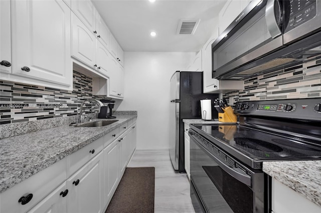 kitchen featuring sink, white cabinetry, light stone counters, black range with electric cooktop, and light hardwood / wood-style floors