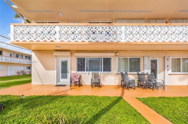 rear view of house featuring a lawn and a balcony