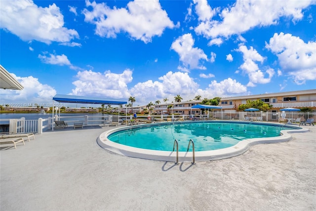 view of swimming pool featuring a water view and a patio